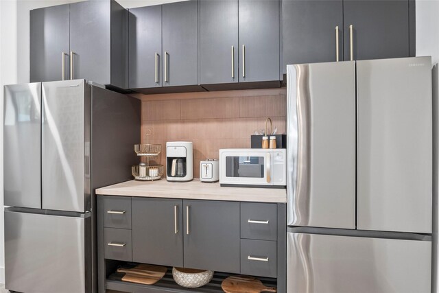 kitchen with visible vents, a sink, dark countertops, a stone fireplace, and a ceiling fan