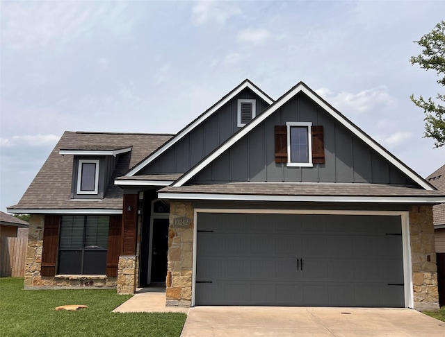 craftsman-style house featuring roof with shingles, a front lawn, stone siding, board and batten siding, and driveway