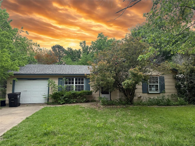 view of front of property featuring concrete driveway, a yard, and a garage