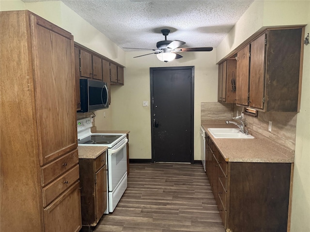 kitchen with white electric range oven, a textured ceiling, a sink, stainless steel microwave, and dark wood-style floors