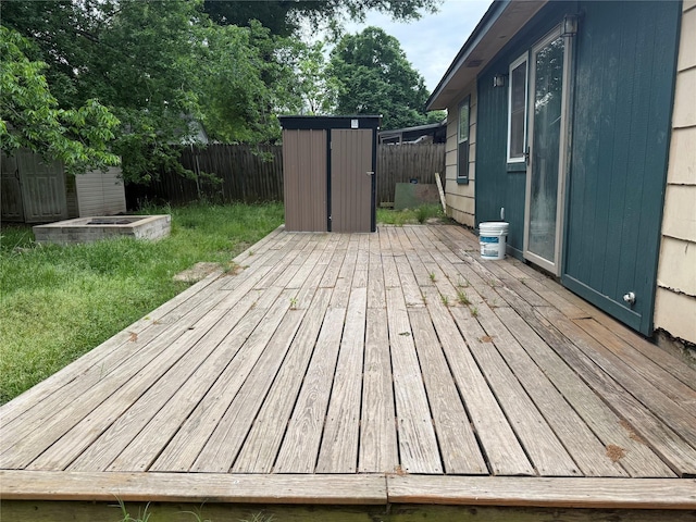 deck with a fenced backyard, an outdoor structure, and a shed