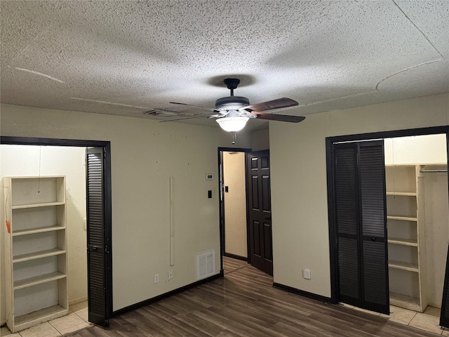 unfurnished bedroom featuring wood finished floors, visible vents, baseboards, a textured ceiling, and ceiling fan