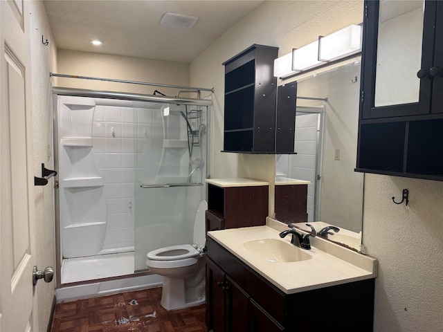 bathroom featuring vanity, a shower stall, and toilet