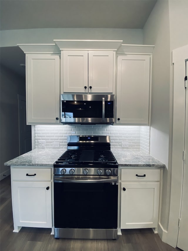 kitchen with stainless steel appliances, white cabinetry, light stone countertops, tasteful backsplash, and dark wood-style flooring