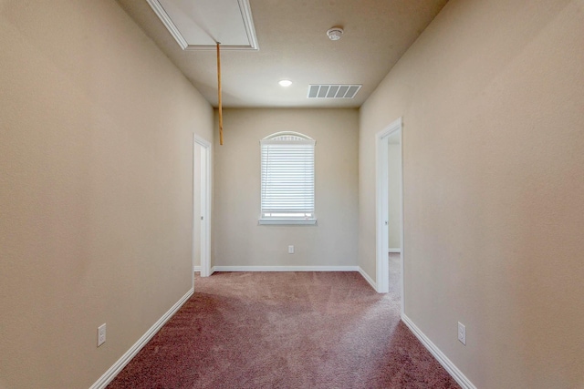 empty room with attic access, baseboards, visible vents, and carpet