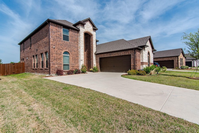 view of front facade featuring an attached garage, brick siding, fence, and a front yard
