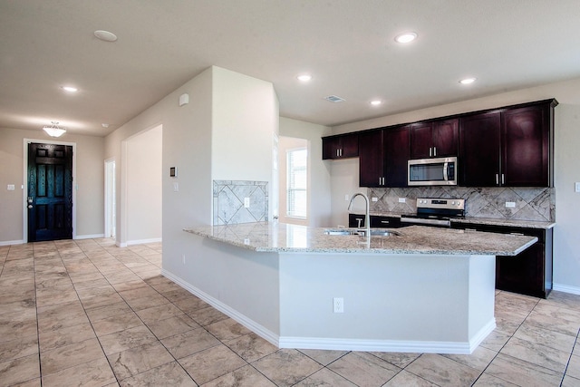 kitchen with light stone counters, tasteful backsplash, stainless steel appliances, and a sink