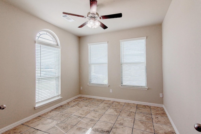 empty room featuring visible vents, a ceiling fan, and baseboards
