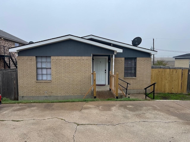 view of front of house featuring fence and brick siding