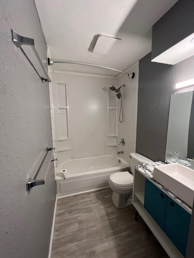 bathroom featuring bathing tub / shower combination, toilet, wood finished floors, a textured wall, and vanity