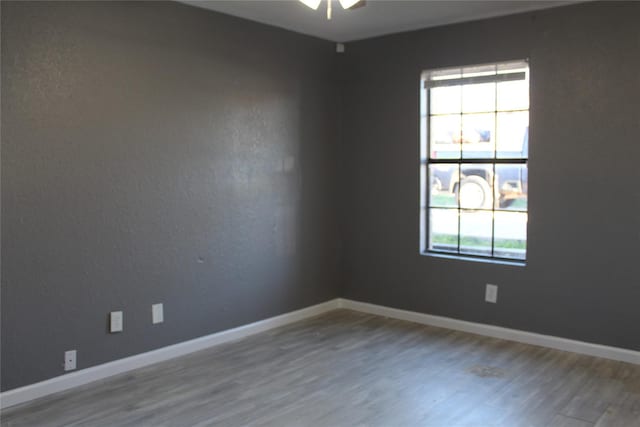 spare room with a wealth of natural light, wood finished floors, and baseboards