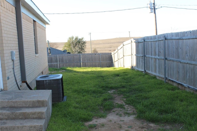 view of yard with central AC and a fenced backyard