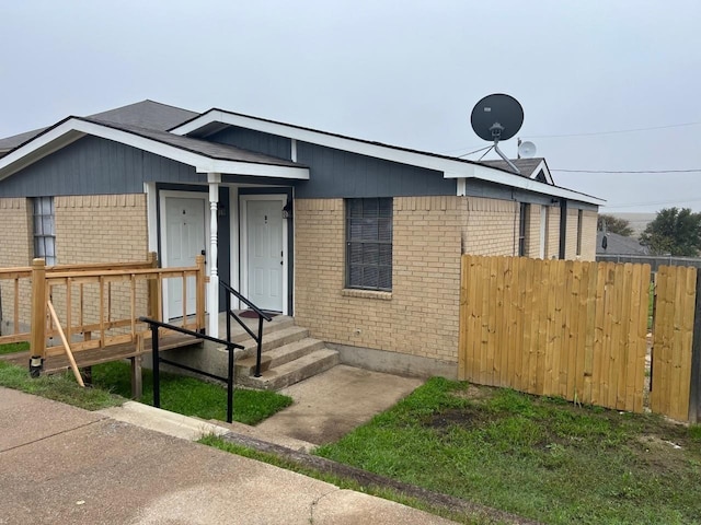 view of front of property with fence, entry steps, and brick siding