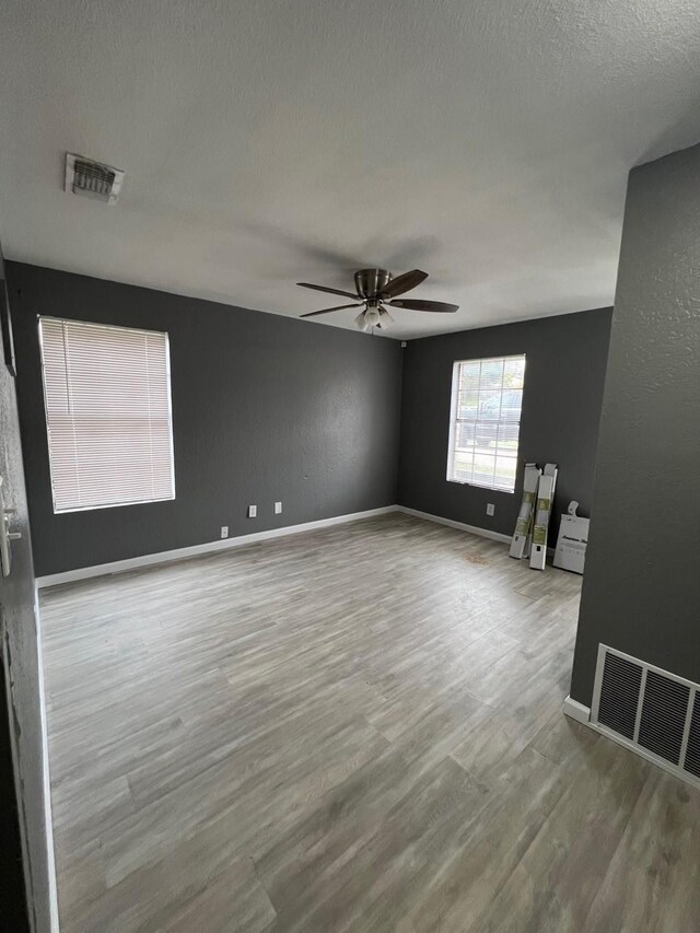 spare room with baseboards, wood finished floors, visible vents, and ceiling fan