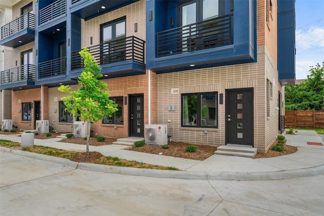 exterior space with brick siding, ac unit, and a balcony