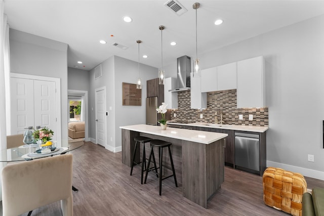 kitchen featuring visible vents, baseboards, a breakfast bar area, wall chimney range hood, and stainless steel appliances