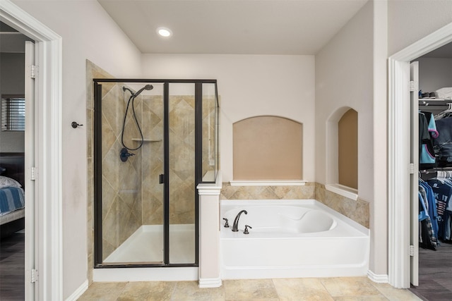 ensuite bathroom featuring ensuite bath, a spacious closet, a shower stall, and a garden tub