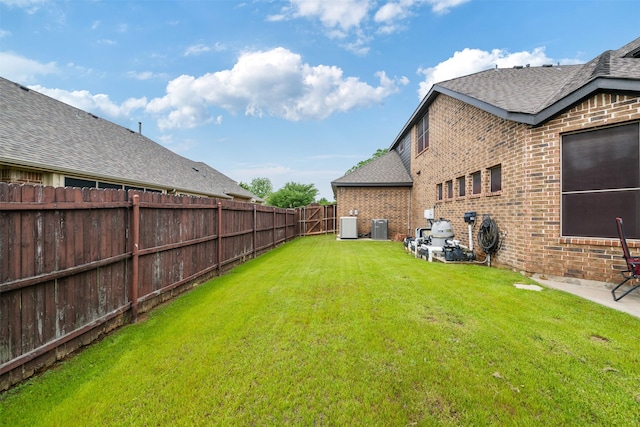 view of yard with fence, a patio area, and central air condition unit