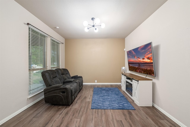 living area with baseboards, wood finished floors, and a notable chandelier