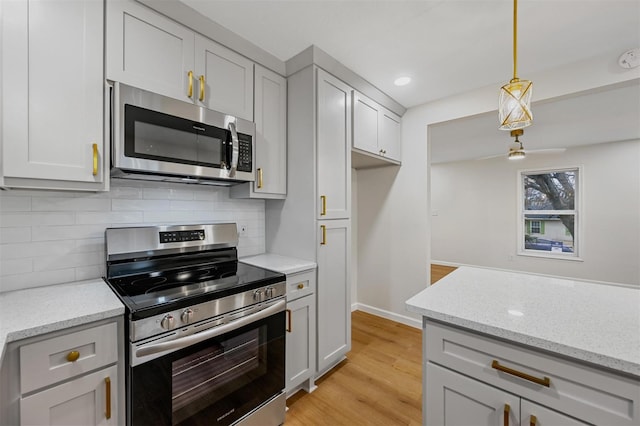 kitchen featuring backsplash, pendant lighting, light stone countertops, and stainless steel appliances