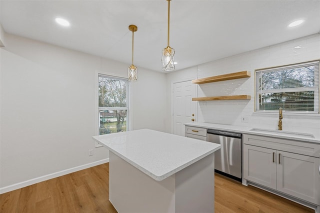 kitchen featuring light wood finished floors, decorative backsplash, stainless steel dishwasher, and a sink