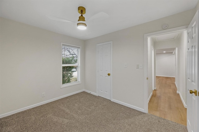 unfurnished bedroom with light colored carpet, ceiling fan, baseboards, and attic access