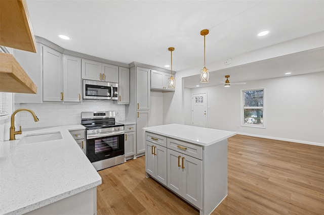 kitchen featuring a sink, light wood-style floors, decorative backsplash, gray cabinets, and appliances with stainless steel finishes