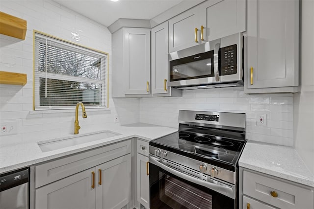 kitchen featuring gray cabinetry, a sink, backsplash, and appliances with stainless steel finishes