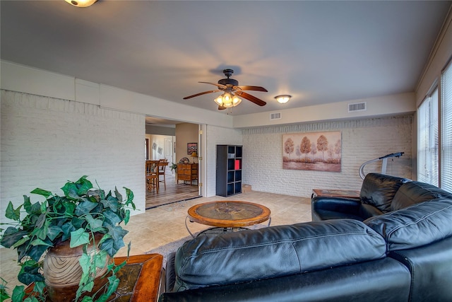living room with brick wall, visible vents, ceiling fan, and light tile patterned flooring