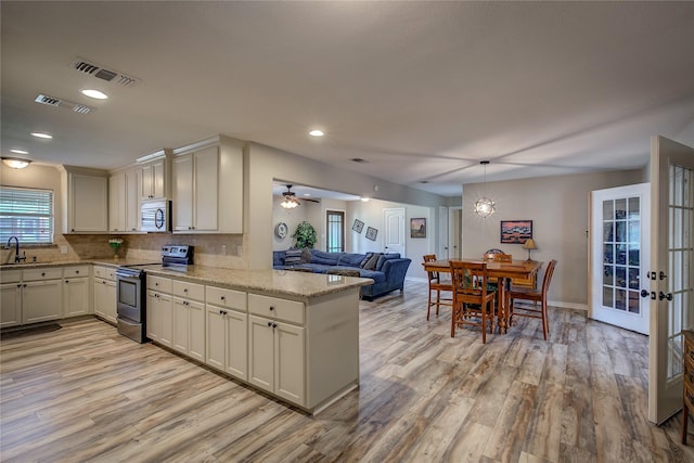 kitchen featuring light wood finished floors, stainless steel appliances, a sink, tasteful backsplash, and visible vents