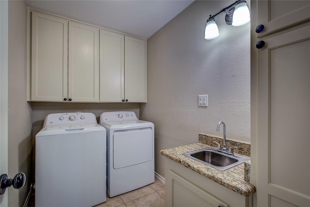 laundry area with a sink, baseboards, cabinet space, washer and dryer, and light tile patterned floors