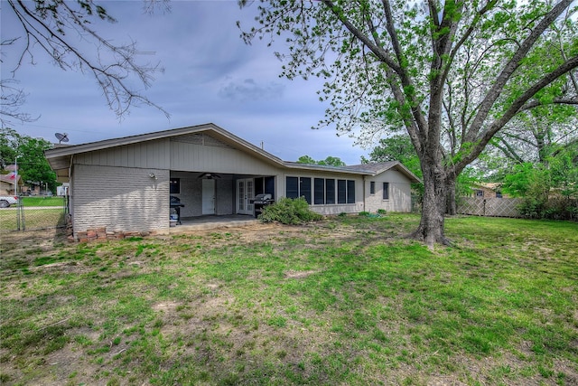 rear view of house featuring brick siding, a yard, a patio, and fence