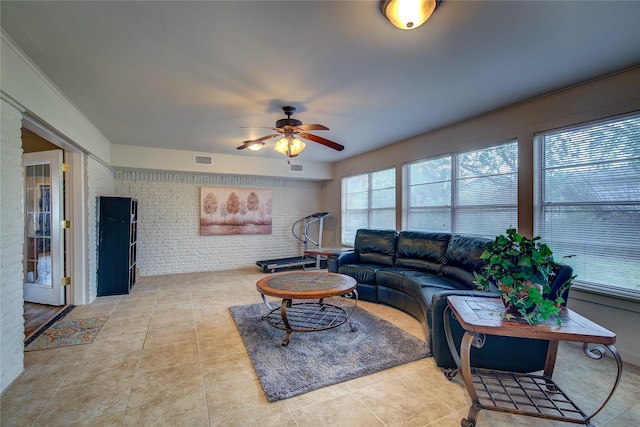living room featuring brick wall, a ceiling fan, visible vents, and light tile patterned flooring