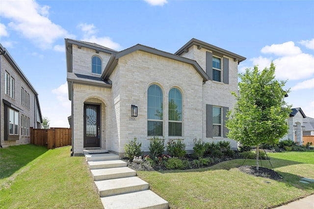 view of front of property featuring fence, brick siding, and a front yard