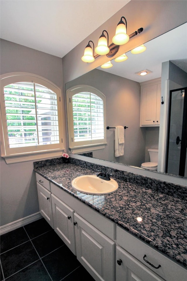 full bathroom with a shower stall, tile patterned flooring, toilet, vanity, and baseboards