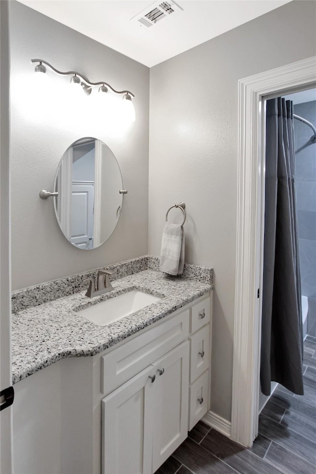 bathroom featuring wood finish floors, a shower with curtain, vanity, and visible vents
