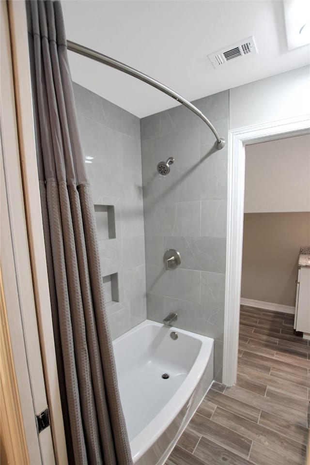 full bath with baseboards, visible vents, shower / tub combo, wood tiled floor, and vanity
