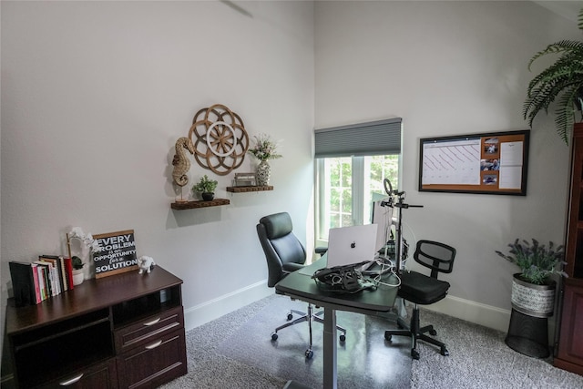 carpeted office space featuring baseboards and a towering ceiling