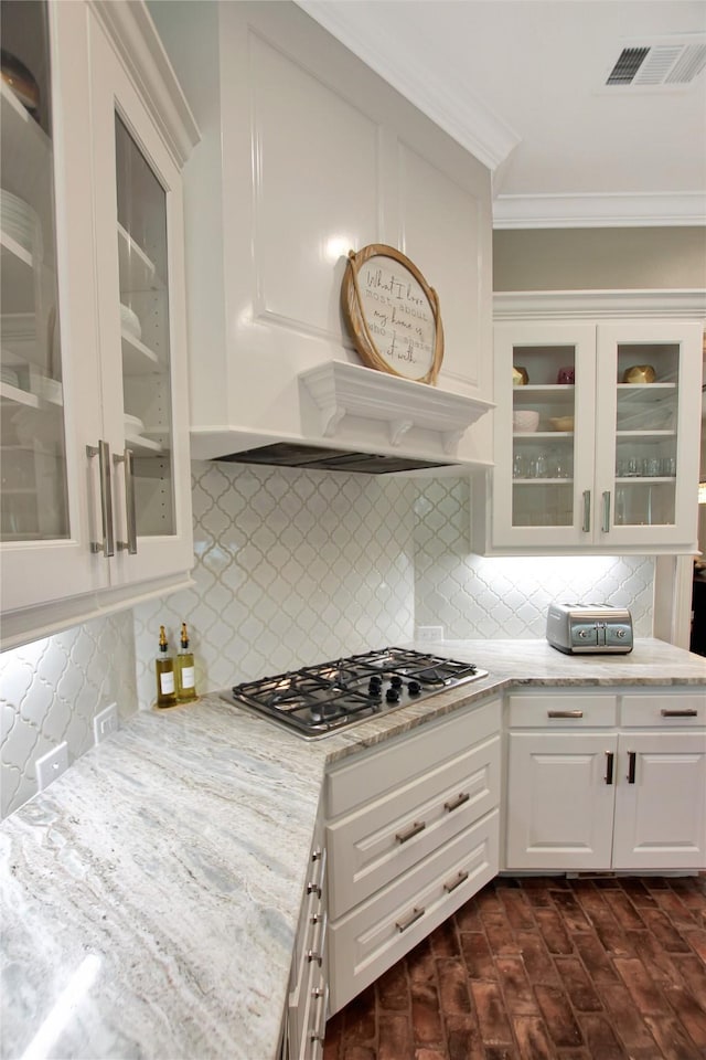kitchen with crown molding, stainless steel gas cooktop, premium range hood, white cabinets, and visible vents