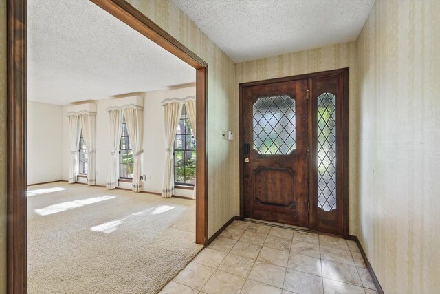 5112 River Ridge Rd, Arlington, TX 76017 - entrance foyer with a textured ceiling, wallpapered walls, baseboards, and light colored carpet