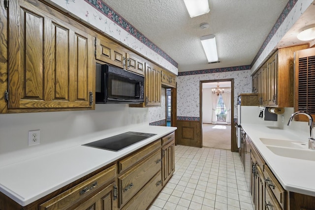 5112 River Ridge Rd, Arlington, TX 76017 - kitchen with wallpapered walls, black appliances, a sink, a textured ceiling, and a chandelier