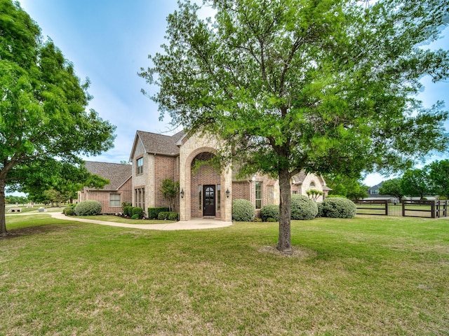 view of front of house featuring brick siding, fence, and a front yard