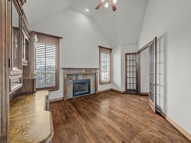 unfurnished living room with a tiled fireplace, vaulted ceiling, dark wood-style floors, and a wealth of natural light