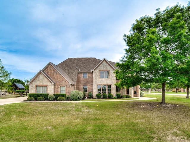 traditional home featuring brick siding, stone siding, and a front lawn