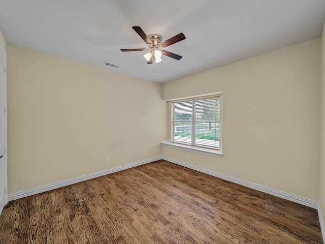 empty room featuring wood finished floors, visible vents, a ceiling fan, and baseboards