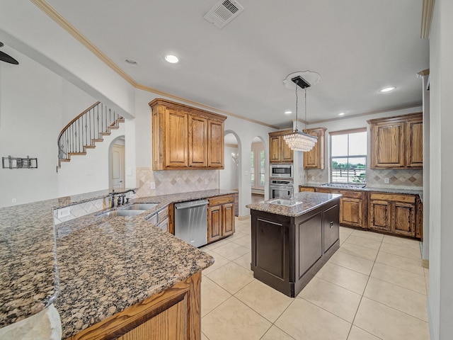 kitchen featuring decorative backsplash, stainless steel appliances, a sink, and arched walkways