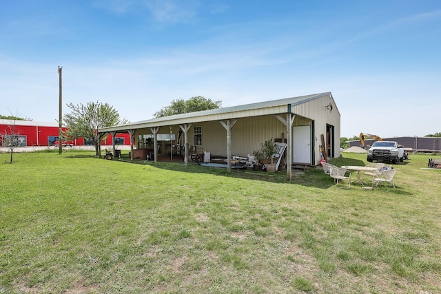 back of property featuring a lawn and an outbuilding