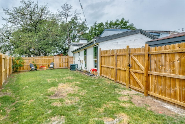 view of yard with a fenced backyard, a gate, and central AC