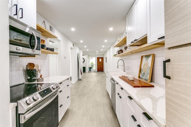 kitchen featuring decorative backsplash, open shelves, stainless steel appliances, and a sink