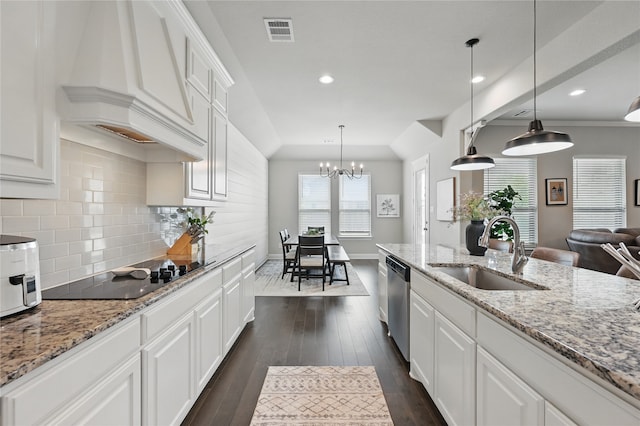 kitchen with a sink, premium range hood, black electric cooktop, stainless steel dishwasher, and white cabinetry
